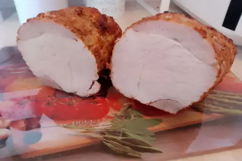 Soczysta szynka pieczona na obiad, pokrojona na pół, z chrupiącą skórką i aromatycznymi ziołami.