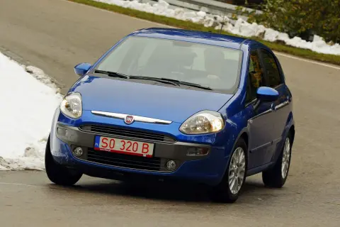 Niebieski Fiat Punto jedzie po drodze, na której widać śnieg. Z przodu widoczne są **czerwone tablice rejestracyjne** z numerem SO 320 B.