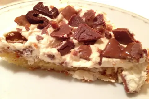 En bit krämig daim tårta med chokladbitar och en chokladdekoration.