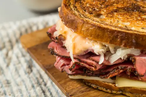 Un delicioso bocata de pastrami con pan tostado, queso fundido y chucrut.