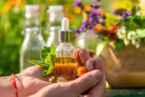Naturalna mikstura na refluks w małej buteleczce z pipetą, otoczona świeżymi ziołami i kwiatami.