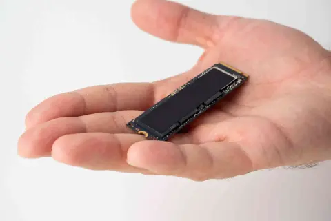 Dłoń trzyma mały dysk SSD M.2. Jego czarna powierzchnia lśni, gotowa do optymalizacji dzięki funkcji ssd trim.