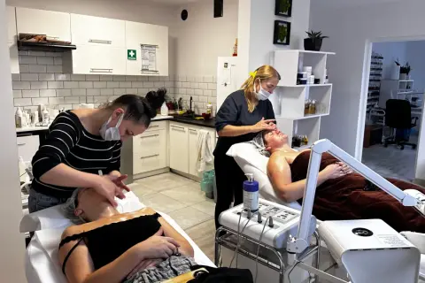 Uczestniczki szkoleń kosmetycznych ćwiczą masaż twarzy na leżących modelkach.