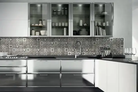 Cucina moderna con ante lucide in acciaio cromato o inox, piastrelle decorate e pensili in vetro.