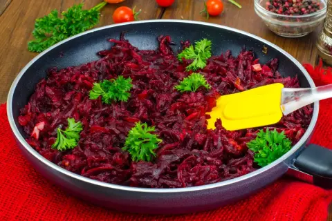 Gotowe buraczki do obiadu, pachnące i gotowe do podania. Żółta łopatka miesza aromatyczne warzywa.