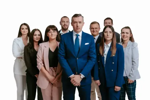 Grupa profesjonalistów w garniturach i kostiumach, pozująca do zdjęcia na białym tle.