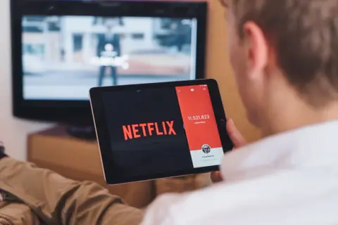 Chcesz wiedzieć, jak podłączyć tablet do telewizora przez HDMI? Na ekranie tabletu widać logo Netflix, a w tle telewizor.