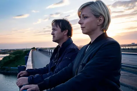 Två personer står på en bro vid solnedgången. En ny dansk serie på Viaplay.