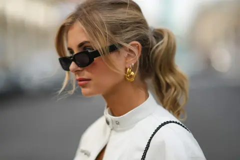 Mujer con coleta y gafas de sol, luciendo un corte de pelo con flequillo cortina que enmarca su rostro.