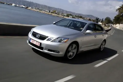 Srebrny Lexus GS300 MK3 pędzi wzdłuż malowniczego wybrzeża z widokiem na zatokę pełną jachtów.