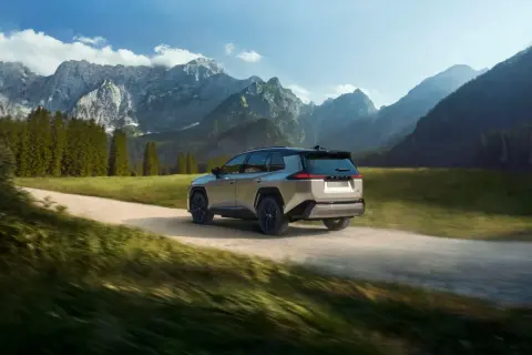 Srebrny Toyota RAV4 pokonuje szutrową drogę w górskim krajobrazie. Idealny do przygód off road.