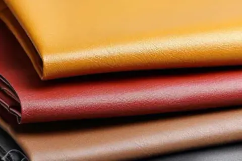 Pile de cuirs enduits aux couleurs vives : jaune, rouge, marron et noir. Ce cuir enduit, c'est quoi ? Une matière synthétique résistante et polyvalente.