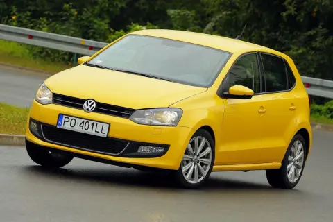 Żółty Volkswagen Polo 6R na mokrej drodze, z tablicą rejestracyjną PO 401LL.