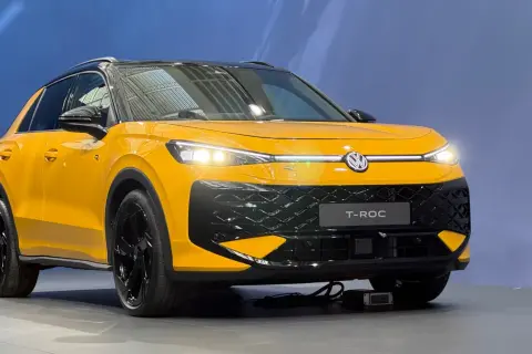 Żółty Volkswagen T-Roc z czarnym dachem i felgami. Zbliżenie na przód auta, gdzie widoczne są światła LED i atrapa chłodnicy. T roc wymiary sugerują kompaktowy SUV.