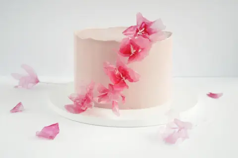 Różowy tort ozdobiony delikatnymi, różowymi kwiatami z masy cukrowej. Inspiracja do stworzenia własnych kwiatów z masy cukrowej krok po kroku.