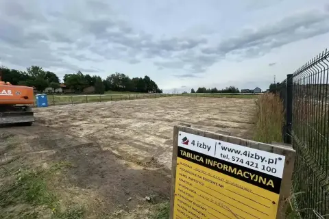 Tablica informacyjna budowy na placu budowy z koparką i toaletą.