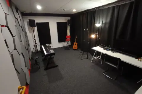 Studio nagraniowe z pianinem, gitarą i mikrofonami. Akustyka pomieszczenia, gdzie może pojawić się jitter, jest poprawiona przez specjalne panele na ścianach.