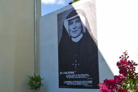 Plakat z portretem św. Faustyny na ścianie budynku, z napisem "ST. FAUSTINA".