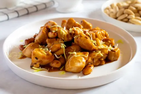 Un invitante piatto di pollo alle mandorle, lucido e saporito, guarnito con erba cipollina.