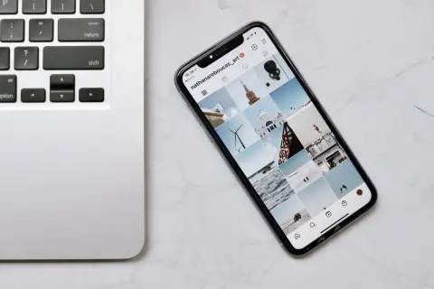 Telefon z Instagramem obok klawiatury laptopa. Dowiedz się, jak połączyć telefon z laptopem, aby łatwo przesyłać zdjęcia.