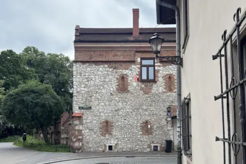 Kamienna ściana z ceglanymi elementami, przypominająca najstarszy dom w Polsce. Ulica Św. Krzyża.