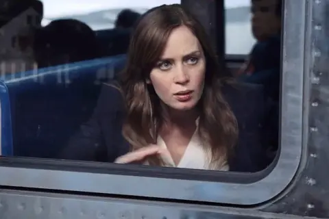 Emily Blunt w filmie, zamyślona, patrzy przez okno pociągu.