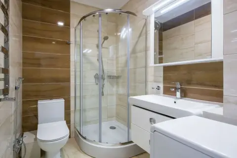 Salle de bain moderne avec douche à l'italienne, lavabo, WC et un banc intégré dans la douche pour plus de confort.