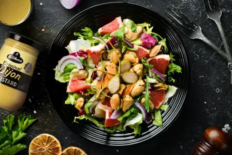 Ensalada fresca con mejillones, pomelo y cebolla morada, aderezada con mostaza de Dijon.