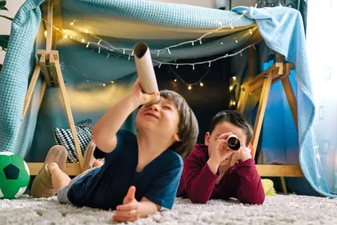 Zwei Jungen erkunden in einer gemütlichen Höhle mit Lichterketten ihre Welt. Perfekte Spiele ab 3 Jahre für fantasievolle Abenteuer.