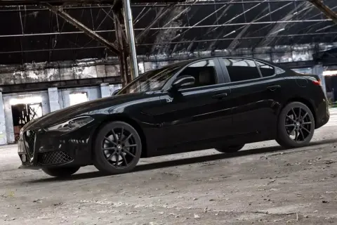 Czarny Alfa Romeo Giulia Quadrifoglio w opuszczonej hali przemysłowej.