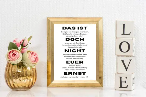 Das Geheimnis einer guten Ehe lustig: Ein gerahmter Spruch über Teamwork und Unterstützung, daneben LOVE-Blöcke und Rosen.