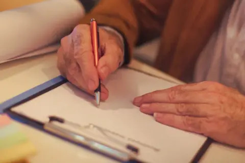 Mężczyzna pisze na papierze, przygotowując się do załatwienia spraw spadkowych bez testamentu.