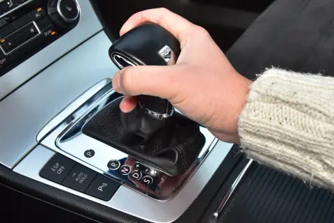 Dłoń na lewarku DSG, pokazująca jak jeździć automatem. Widoczne przyciski ESP, Auto Hold i wybór biegów P, R, N, D, S.
