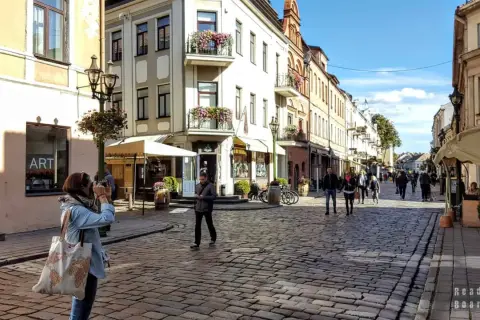 Spacer po urokliwej uliczce w Kownie, gdzie leży to piękne miasto. Kobieta robi zdjęcie zabytkowej kamienicy.