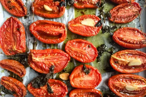 Tomates au four, coupées en deux, rôties avec de l'ail et des herbes, leur chair concentrée et savoureuse.