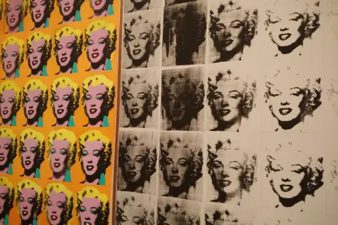 Wielokrotne portrety Marilyn Monroe w stylu serigrafia pop art, w jaskrawych kolorach i czarno-białych wersjach, tworzą ikoniczną kompozycję.