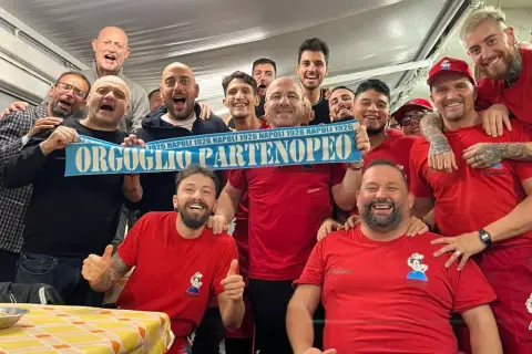Un gruppo di tifosi esulta con una sciarpa "Orgoglio Partenopeo" e magliette con scritto "Nennella Napoli".