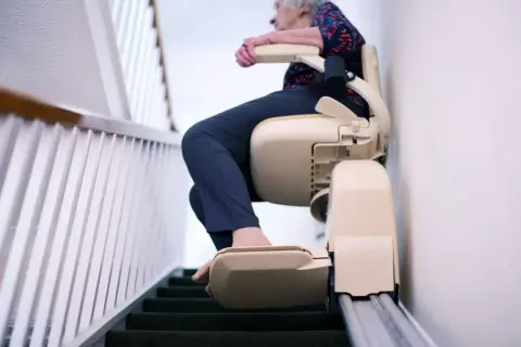 Anziana su montascale mobile senza installazione, che sale le scale con facilità e sicurezza.