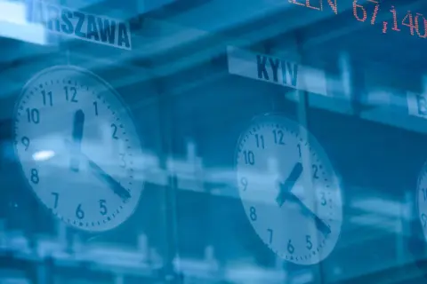 Zegary pokazujące czas w Warszawie i Kijowie, a nad nimi kursy akcji.
