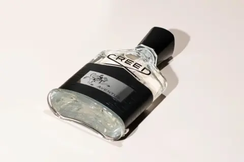 Elegancka butelka perfum Aventus Creed z czarną opaską i wizerunkiem jeźdźca.