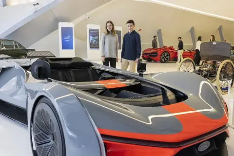 Jóvenes observan coches futuristas y clásicos en una exposición de coches en Zaragoza.