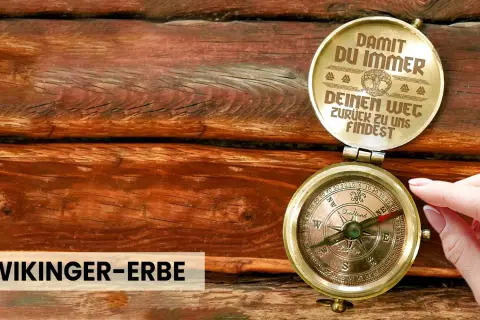 Ein antiker Kompass auf Holz, der dazu ermutigt, dem Leben zu vertrauen und immer den Weg zurückzufinden. "Wikinger-Erbe" steht darunter.
