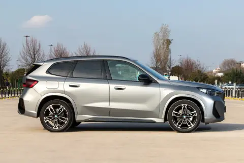 Srebrny, niezawodny SUV BMW X1 stoi na parkingu. Elegancki design i sportowe felgi podkreślają jego charakter.