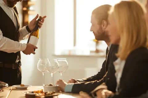 Ein Sommelier präsentiert eine Weinflasche. Seine Expertise zeigt die wahre sommelier bedeutung.