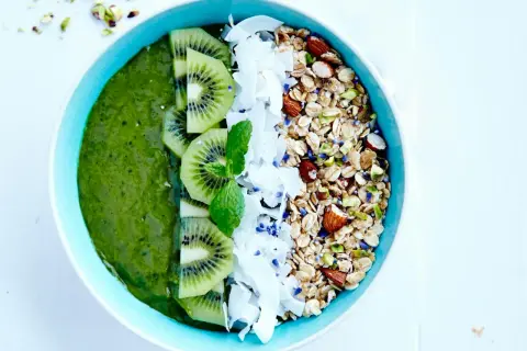 En grön, nyttig smoothie bowl med kiwi, kokosflingor och granola.