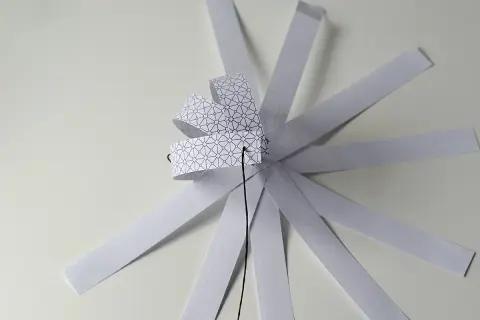 Papierowa ozdoba choinkowa 3D w trakcie tworzenia, z pasków z geometrycznym wzorem.