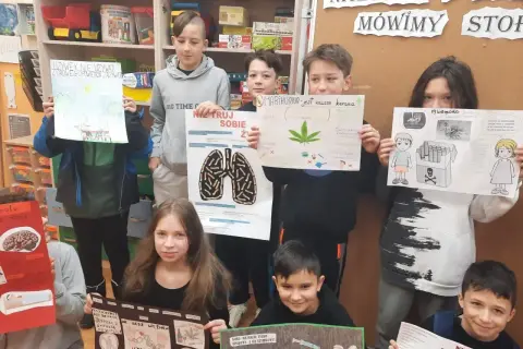 Dzieci prezentują plakaty o szkodliwości używek, pokazując jak zrobić projekt artystyczno-edukacyjny.