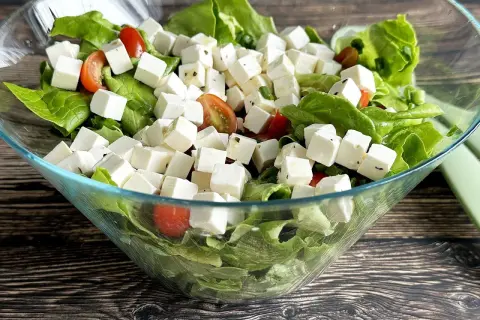 Sałatka z kostkami tofu, która smakuje jak feta. Zielona sałata, pomidorki koktajlowe i tofu w szklanej misie.
