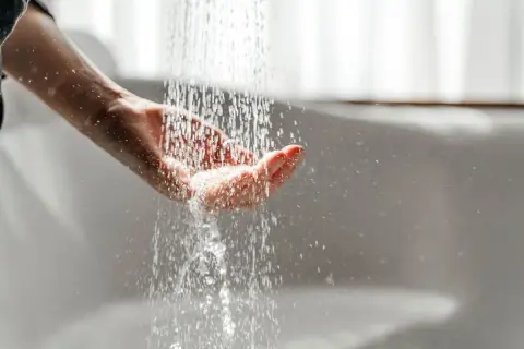 Hand fängt Wasser auf. Mögliche Legionellen im Wasser können zu einer Mietminderung führen.