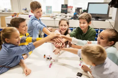 Kinder legen ihre Hände in der Mitte zusammen, ein Zeichen für Teamwork in ihrem mint kita-Projekt.